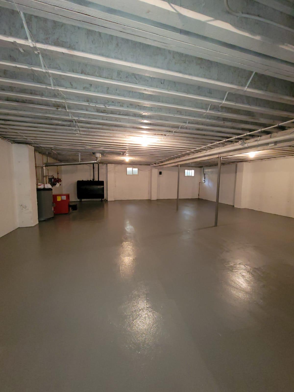 Basement with cleaned ceiling joists and sealed floor after mold remediation in New York